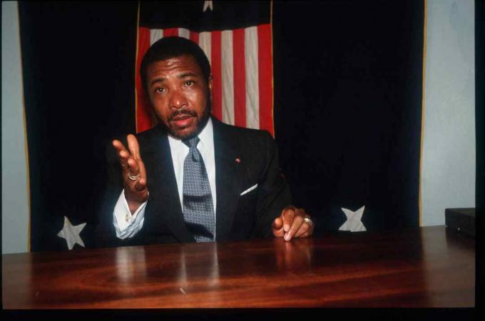 Charles Taylor sedí před vlajkou Libérie