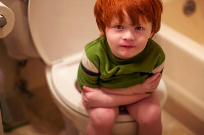 Malý chlapec sedí na záchodě