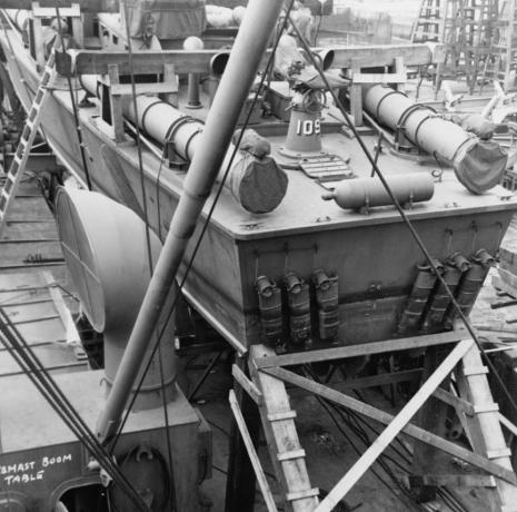 Záď PT-109 na palubě nákladní lodi se šesti viditelnými tlumiči výfuku a dřevěným ztužením pro cestu do Tichého oceánu.