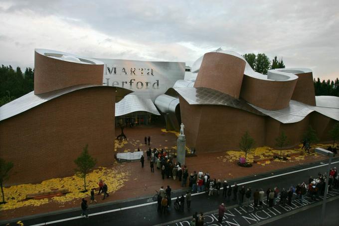 dlouhý pohled na zvlněnou kovovou střechu na budově z červených cihel s názvem MARTa Herford - Lidé se zaradí do muzea „MARTa“ 7. května 2005 v německém Herfordu. Muzeum současného umění a designu navržené americkým hvězdným architektem Frankem Gehrym nabízí výstavní plochu 2 500 metrů čtverečních a bylo dokončeno po čtyřech letech výstavby.