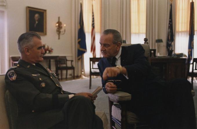 Generál William Westmoreland, v uniformě americké armády a se sídlem, hovoří s prezidentem Lyndonem B. Johnson v oválné kanceláři.