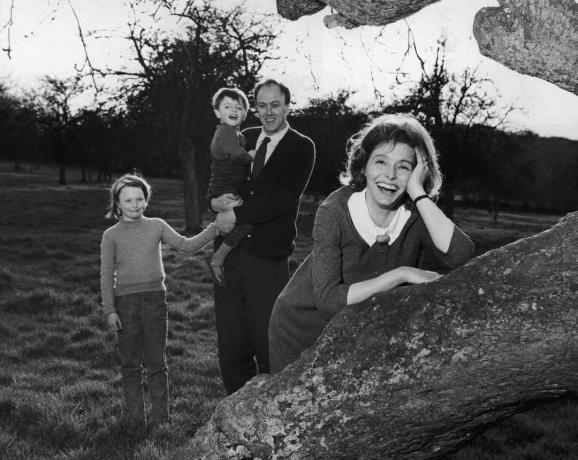 Černobílá fotografie Roalda Dahla, který držel své děti; jeho žena Patricia Neal se opře o strom