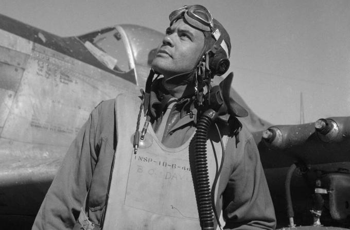 Benjamin O. Davis v obleku a helmě stojící před bojovníkem Mustangu P-51.