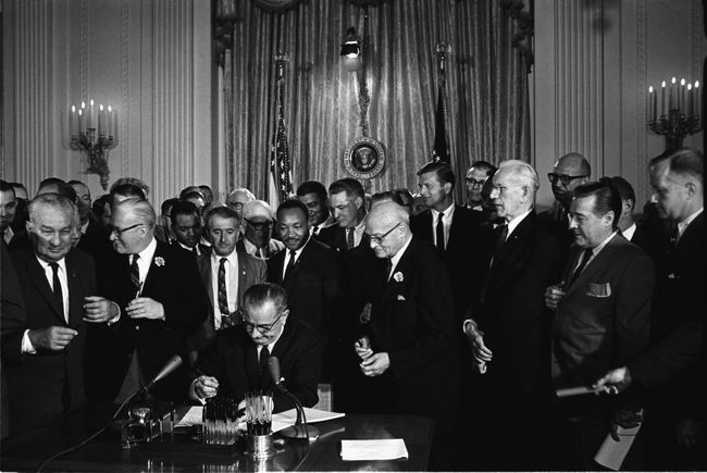 Prezident Lyndon B. Johnson podepisuje zákon o občanských právech z roku 1964 jako Martin Luther King, Jr. a další, podívejte se.