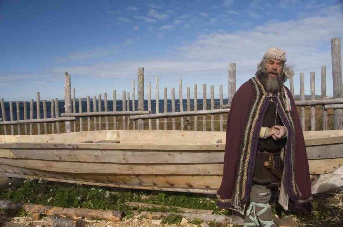 Vikingský herec v typickém oděvu před replikou dlouhých lodí, L'Anse Aux Meadows, Newfoundland