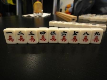 Postava obleku sady dlaždic Mahjong sedí na stole.