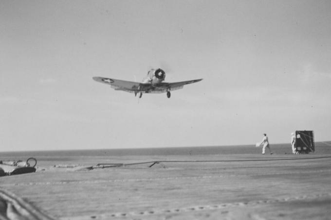 Jednomotorový potápěčský bombardér se chystá přistát na letadlové lodi USS Ranger.