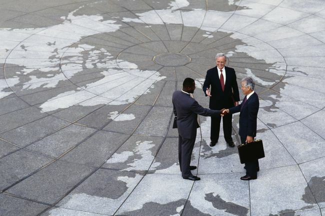  Ekonomický regionalismus: Podnikatelé potřesení rukou na mapě zeměkoule.
